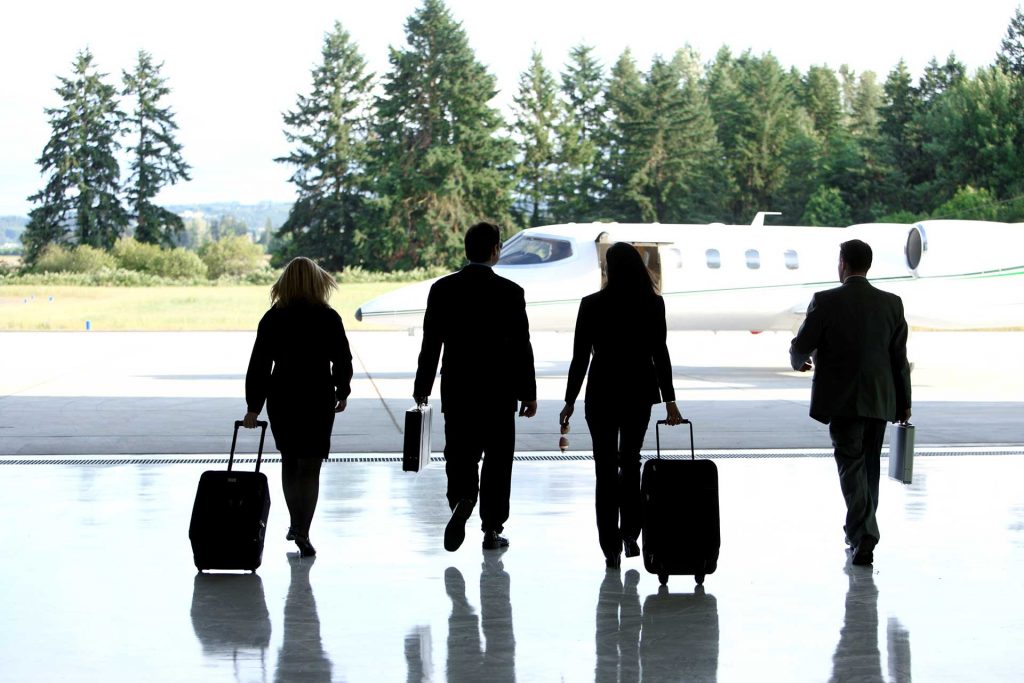 A flight crew of four walks to their aircraft with luggage